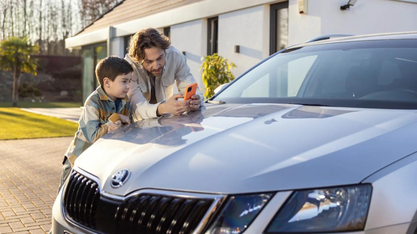 Un père et son fils estiment leur voiture en ligne sur un smartphone