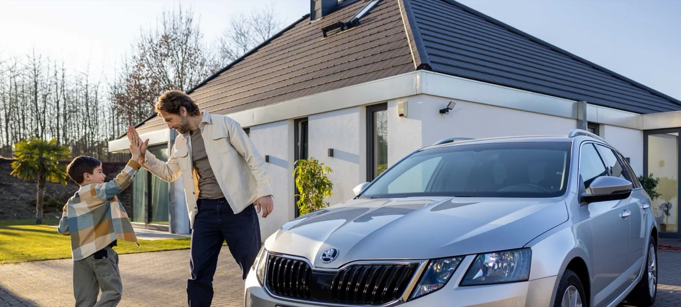 Un père et son fils se tapent dans la main devant leur voiture, contents de leur offre